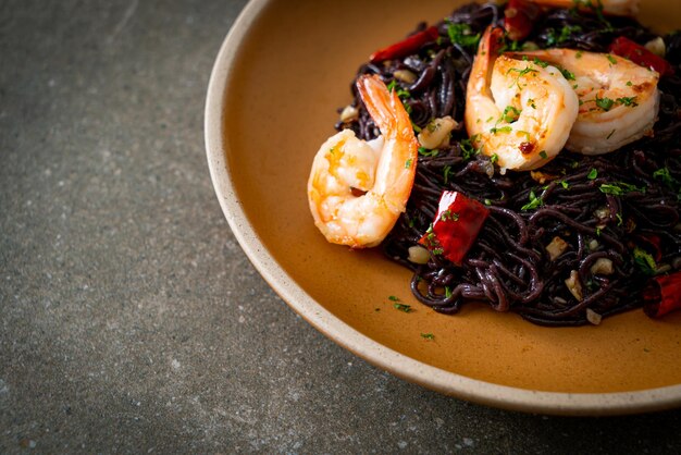 spaghettis noirs sautés à l'ail et aux crevettes sur assiette