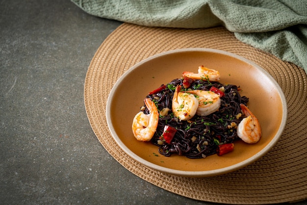 spaghettis noirs sautés à l'ail et aux crevettes sur assiette