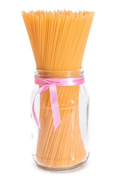 Des spaghettis secs non cuits dans un pot en verre isolé sur un fond blanc