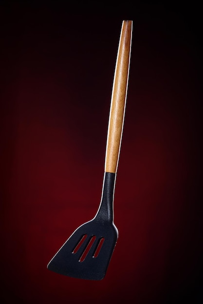 Spatule de cuisine pour tourner la viande Ceci est une photo promotionnelle d'ustensiles de cuisine sur fond sombre