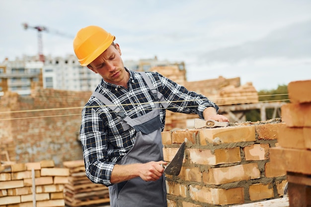 Avec une spatule pour la construction Ouvrier en uniforme et équipement de sécurité a un travail sur la construction