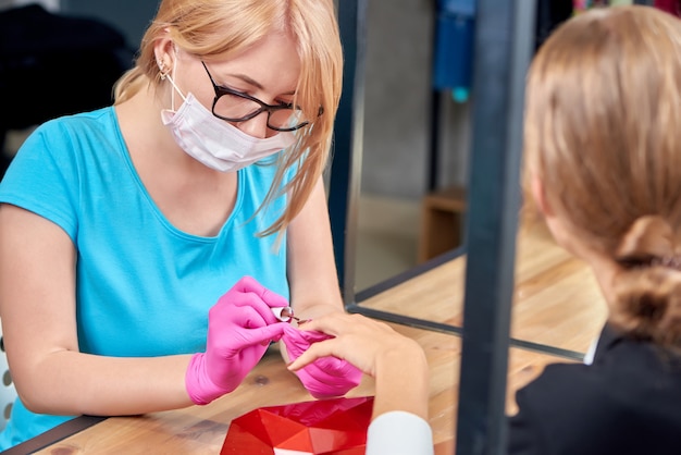 Spécialiste de la beauté féminine en train de faire de la manucure pour femme dans un salon moderne.