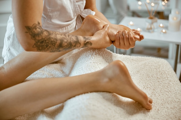 Un spécialiste caucasien professionnel fait un message de jambe dans un salon minimaliste moderne