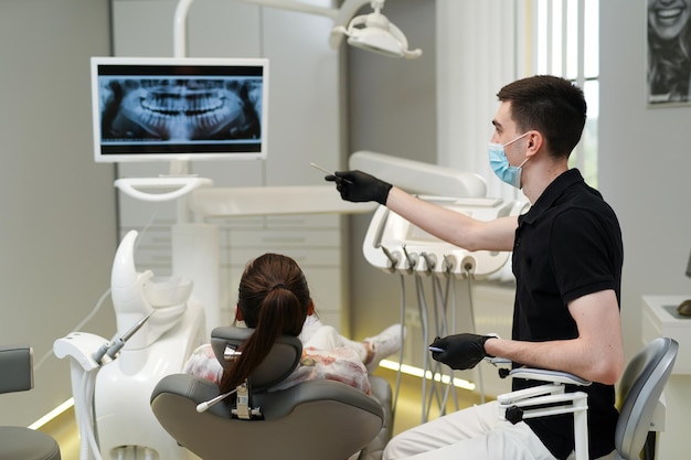 Spécialiste dentaire professionnel travaillant avec la santé des dents des patients. Patient ayant un examen dentaire avec moniteur.