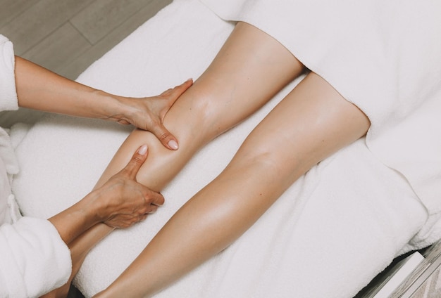 Photo un spécialiste donne à une femme un massage relaxant des pieds sur une table dans un salon de spa