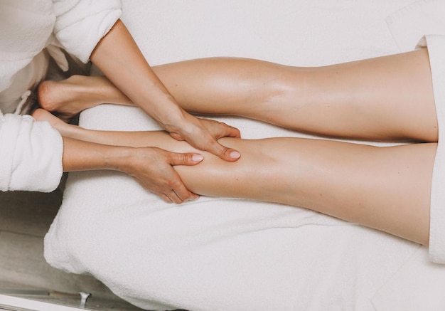 Photo un spécialiste donne à une femme un massage relaxant des pieds sur une table dans un salon de spa