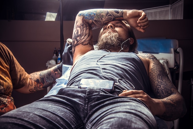 Un spécialiste du tatouage crée un tatouage dans un studio de tatouage./Tatoueur au travail dans un salon de tatouage.