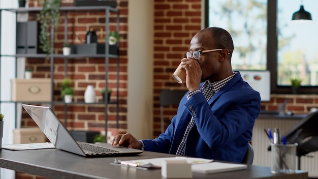 Spécialiste de l'entreprise analysant les statistiques en ligne sur le site Web, utilisant le rapport Internet pour écrire des e-mails sur un ordinateur portable. Employé de bureau planifiant la présentation du projet de démarrage avec l'application de la paperasserie. Prise de vue au trépied.