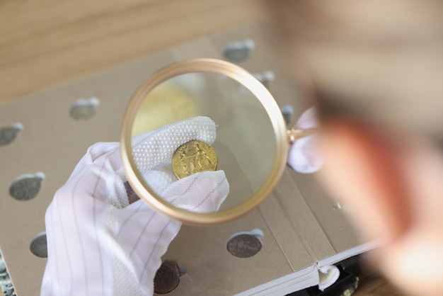 Spécialiste ganté examinant la pièce d'or avec une loupe