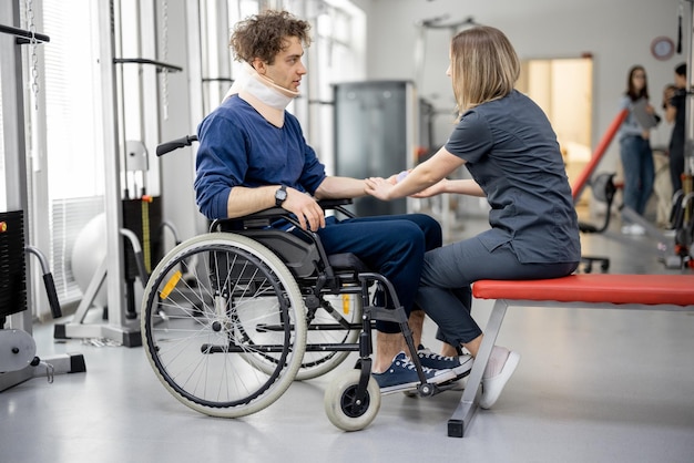 Spécialiste de la réadaptation avec un gars en fauteuil roulant faisant de l'exercice
