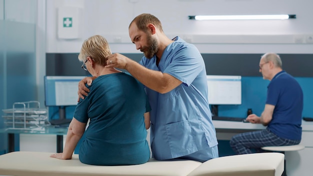 Spécialiste De La Santé Effectuant Une Procédure D'ostéopathie Sur Un Patient âgé Souffrant De Blessures Physiques, Fissurant Les Os De La Moelle épinière Pour La Récupération. Physiothérapeute Aidant Une Femme à La Médecine Alternative Au Bureau.