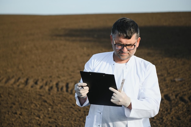 Spécialiste vérifiant la qualité du sol avant la plantation et autre main tenant un cahier et un stylo concept amélioration du sol pour l'agriculture