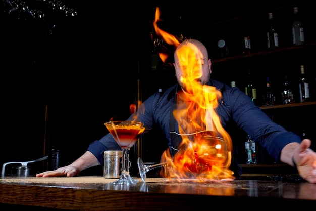 Spectacle enflammé au bar. Le barman prépare un cocktail alcoolisé chaud et allume le bar. Le barman prépare un cocktail fougueux. Feu sur barre.