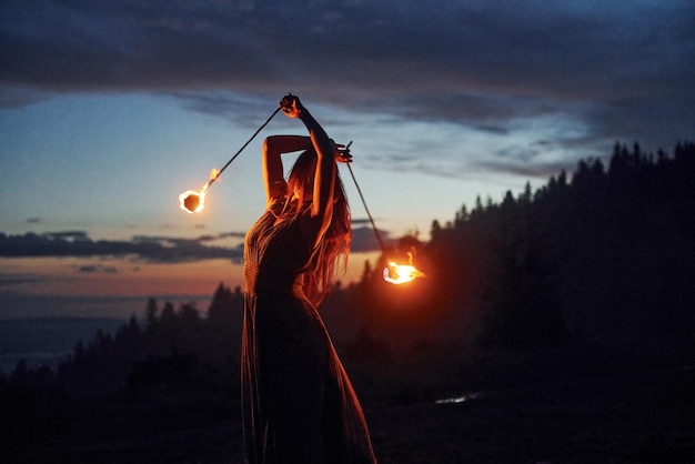 Spectacle de feu par une femme en robe dans la nuit Montagnes des Carpates Beau paysage