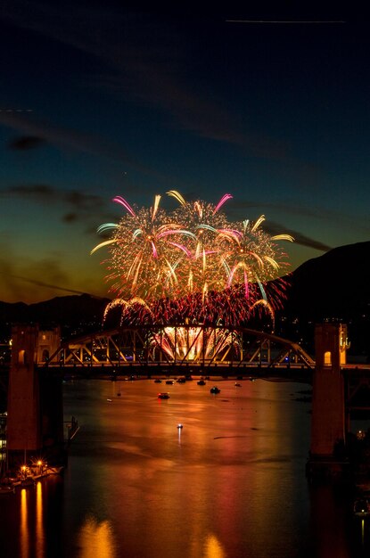 Photo spectacle de feux d'artifice sur la rivière contre le ciel la nuit