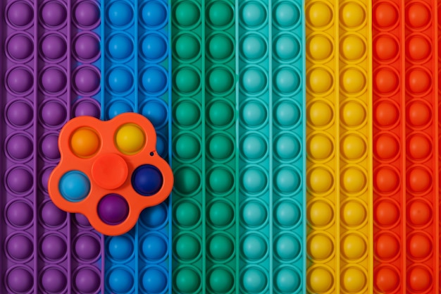 Spinner à jouet tendance Simple Dimple sur une surface multicolore POP IT. Appuyez sur bulle, jeu de doigts.