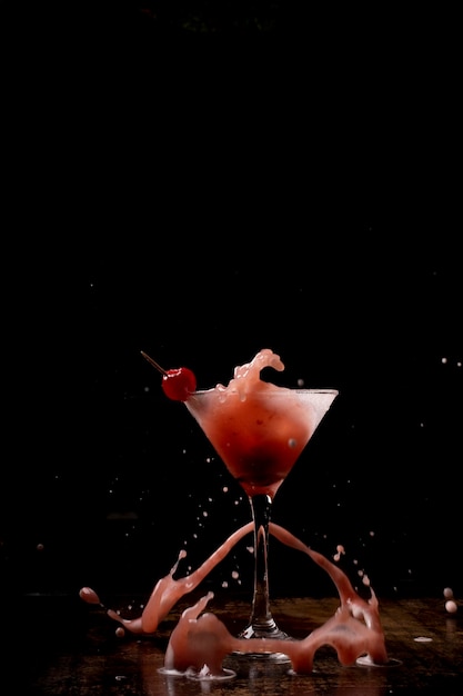 Photo splash de cocktail cherry martini tourné sur un comptoir en bois avec un fond sombre