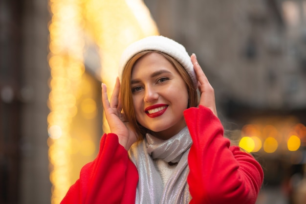 Splendide jeune femme en manteau rouge marchant à la foire de rue