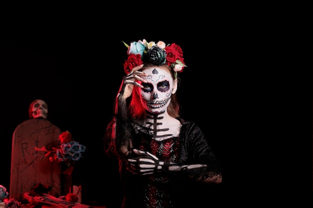 Spooky lady of dead avec bandeau de fleurs posant en studio comme saint santa muerte et la cavalera catrina. Jeune femme agissant glamour avec costume noir et blanc, jour de la tradition morte.