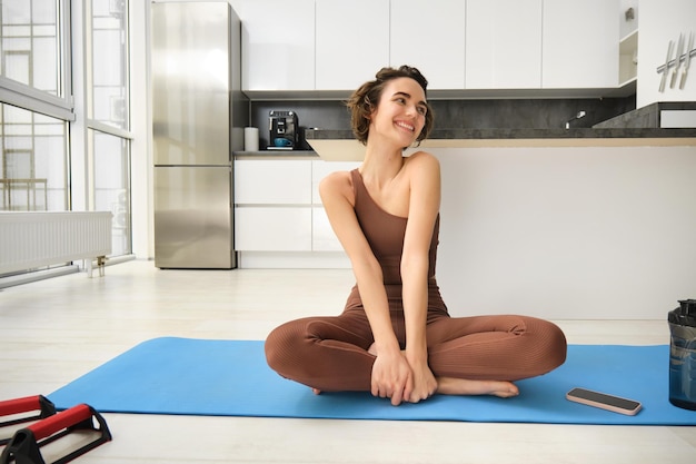 Sport et bien-être jeune brunette fitness girl wearing activewear assis sur un tapis de yoga méditant pr