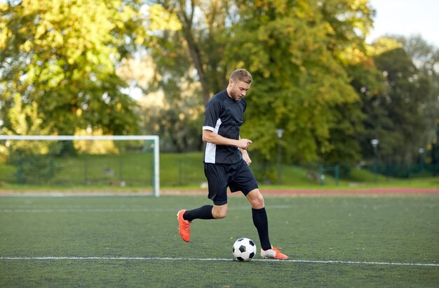 sport, entraînement de football et personnes - joueur de football jouant avec le ballon sur le terrain