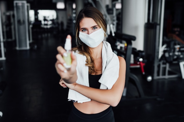 Photo sport sûr, entraîneur personnel dans un masque de protection au milieu d'une salle moderne.