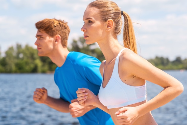 Le sport est notre vie. Cheerful young woman and man in sportswear longeant la berge