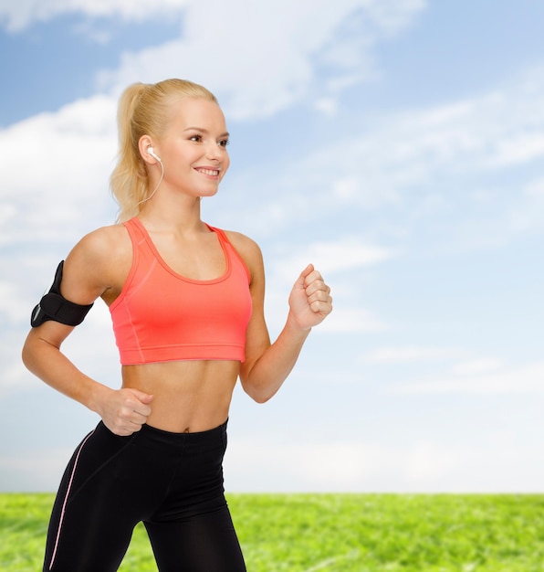 sport, exercice, technologie, internet et soins de santé - femme sportive souriante courant et écoutant de la musique depuis un smartphone