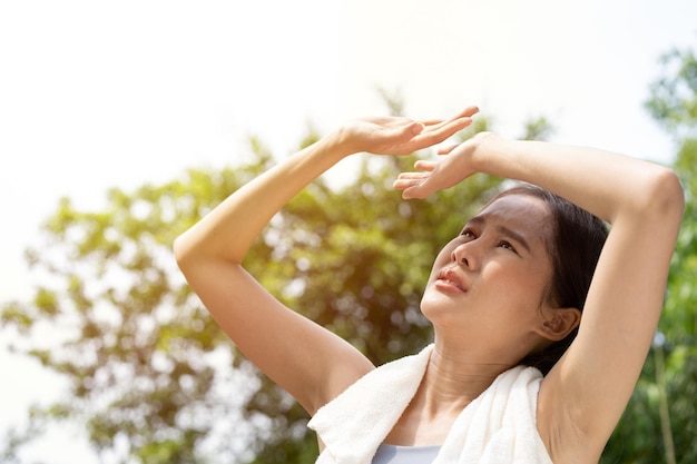 Photo sport la femme asiatique se fatigue et se sent étourdie ressent de mauvaises douleurs et souffre d'un coup de chaleur à l'extérieur lors de jogging ou d'exercice en plein air avec une forte lumière du soleil en été concept de coup de chaud et de vague de chaleur