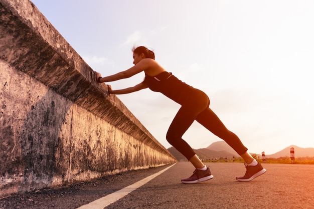 Sport femme coureur étirement musculaire avant de courir sur la longue route