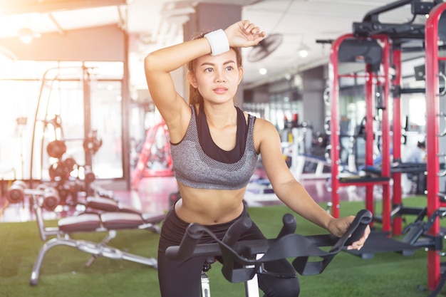 Sport femme exercice à vélo dans la salle de gym le matin