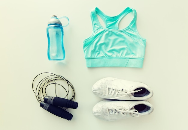 sport, fitness, mode de vie sain, entraînement cardio et concept d'objets - gros plan sur des vêtements de sport féminins, une corde à sauter et un ensemble de bouteilles