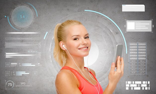 Photo sport, fitness et technologie - jeune femme heureuse avec smartphone et écouteurs écoutant de la musique sur fond de béton gris