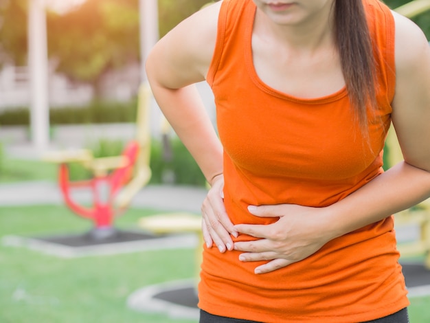 Sport girl a mal au ventre après un jogging dans le parc.