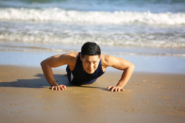 Sport homme faisant des exercices sur la plage le matin