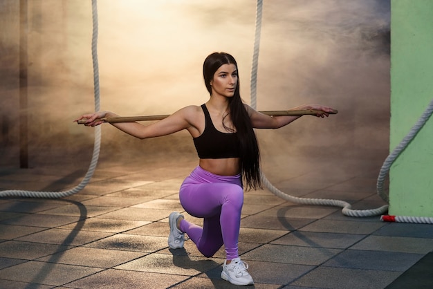 Sport jeune femme faisant accroupi avec haltères dans la salle de gym.