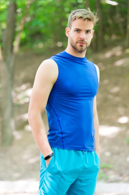 Sport jeunesse. Beau jeune sportif profitant d'activités sportives le jour d'été. Homme athlétique en vêtements de sport sur paysage naturel. Sport, remise en forme et loisirs.