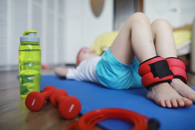 Sport et mode de vie sain. Enfant faisant du sport à la maison. Tapis de yoga haltère et corde à sauter. Contexte sportif avec concept d'exercices à domicile.