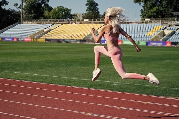 Sport mode de vie sain femme sexy avec des fesses serrées femme athlétique en plein air en vêtements de sport en cours d'exécution sur le stade femme coureur femme entraîneur de fitness yoga et pilates prêt à courir