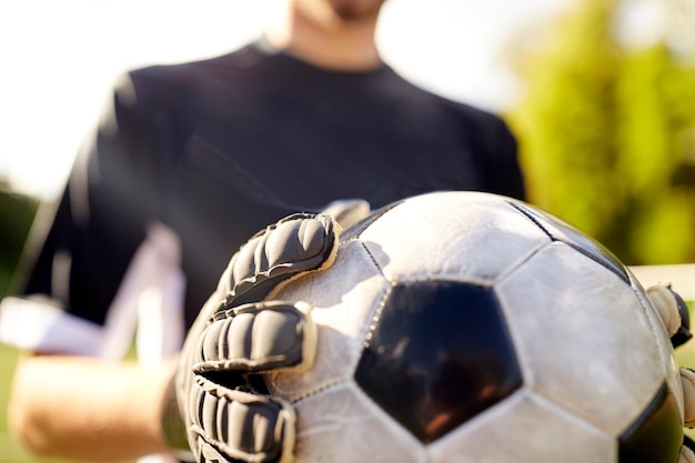 Photo sport et personnes - gros plan sur un joueur de football ou un gardien de but tenant le ballon au but de football sur le terrain