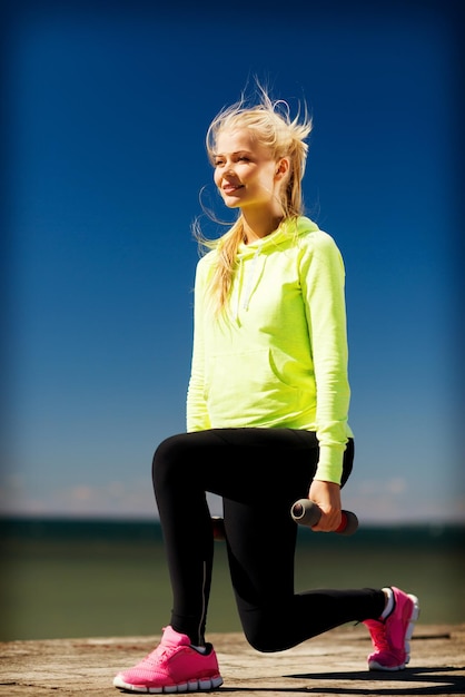 sport et style de vie - jeune femme sportive avec des haltères légers à l'extérieur