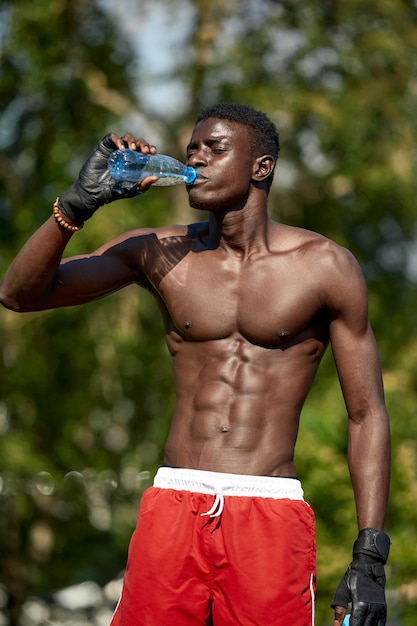 Sportif afro-américain buvant de l'eau douce après l'entraînement.