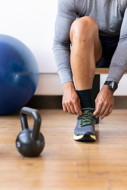 Sportif attachant ses lacets dans la salle de sport