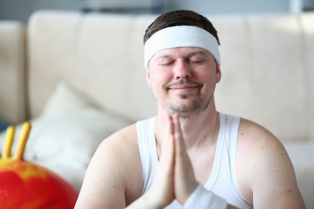 Sportif aux yeux fermés Portrait de visage souriant. Homme barbu faisant la méditation de yoga avec les mains ensemble. Sport intérieur paisible.