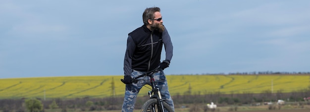 Sportif barbu brutal sur un vélo de montagne moderne Belle vue depuis la montagne Vue panoramique pour bannière