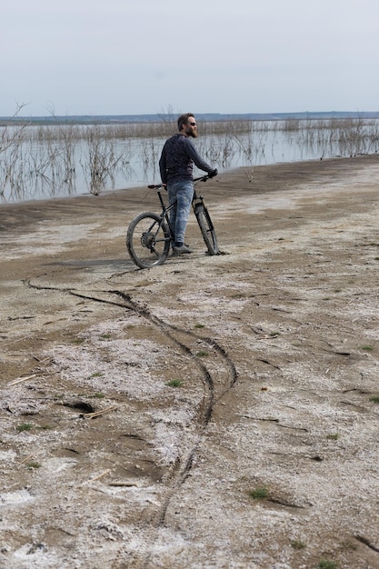 Sportif barbu brutal sur un VTT moderne Un cycliste dans un endroit déserté de sel au bord du lac