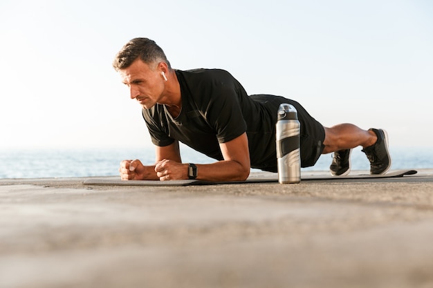 Sportif confiant dans les écouteurs faisant planche