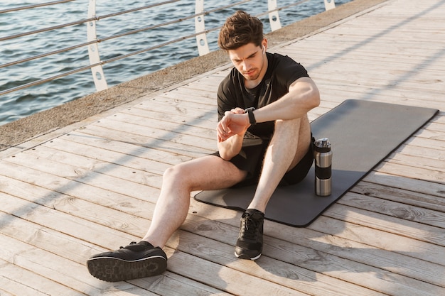 Sportif à l'extérieur regardant la montre.