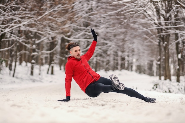 Sportif faisant des exercices d'échauffement lors d'une journée d'hiver enneigée en forêt. Fitness hivernal, vie saine