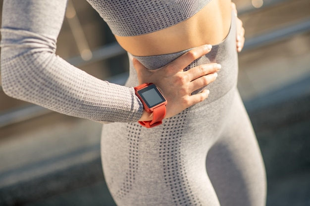 Sportif. Gros plan photo d'une femme en vêtements de sport gris et avec une montre connectée au poignet